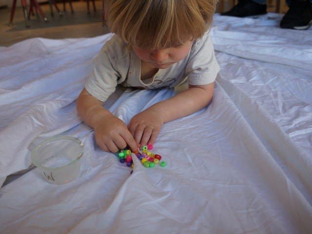 child selecting beads for art project